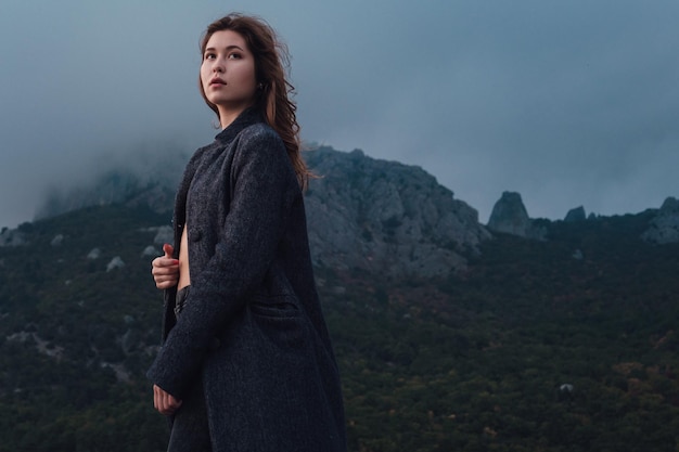 Donna asiatica in un cappotto grigio che gode della vista sulle montagne