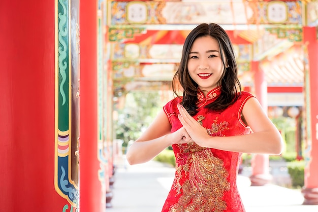 Donna asiatica in vestito rosso tradizionale che fa saluto