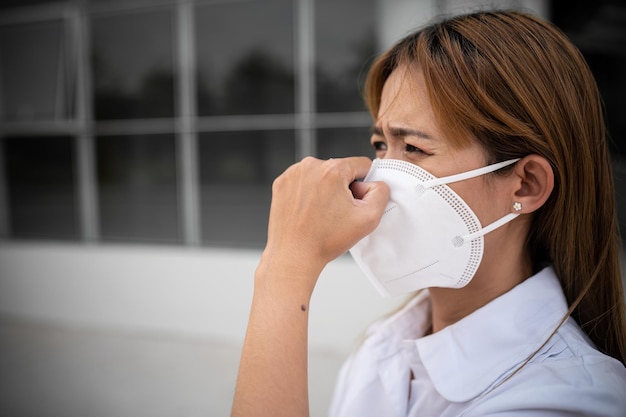 Donna asiatica indossa maschera N95 per proteggersi dalla polvere pm 25 concetto di ecologia Allergia mal di testa pericolo aereo in città