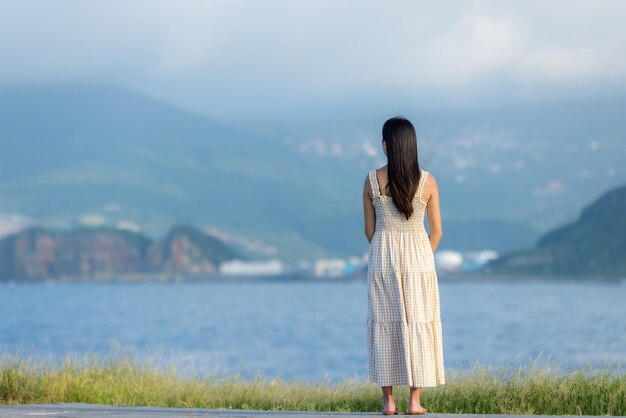 Donna asiatica indossa un vestito e guarda il mare