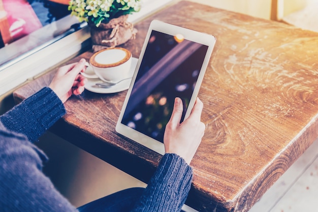 donna asiatica mano che tiene tavoletta e utilizzando tablet in caffè con annata tonica.