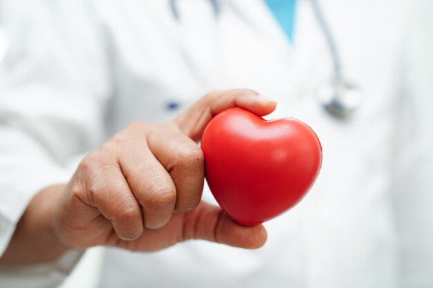 Donna asiatica medico che tiene cuore rosso per la salute in ospedale