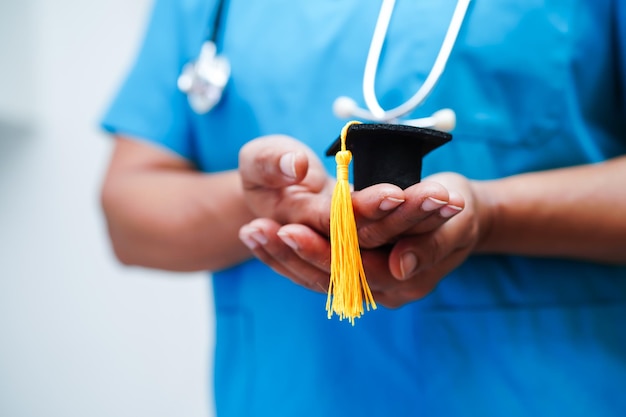 Donna asiatica medico che tiene il cappello di laurea in ospedale Concetto di educazione medica