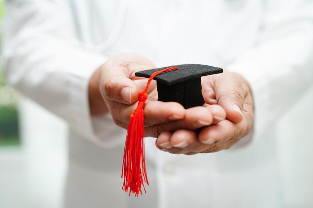 Donna asiatica medico che tiene il cappello di laurea in ospedale Concetto di educazione medica