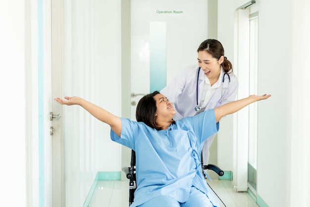 Donna asiatica medico e paziente donna grassa che seduto sulla sedia a rotelle Sorridente e felice insieme