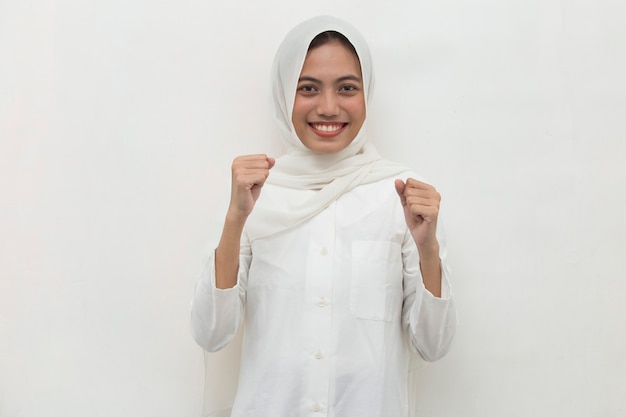 Donna asiatica musulmana felice ed emozionata che celebra la vittoria che esprime grande energia di potere di successo ed emozioni positive