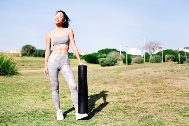 Donna asiatica pronta con il suo tappetino per una sessione di yoga