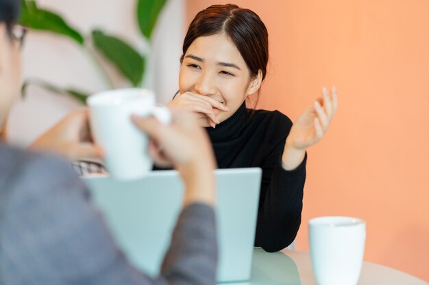 Donna asiatica seduta e chiacchierando con i colleghi nella caffetteria dopo il lavoro
