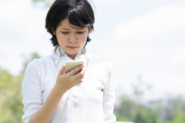 Donna asiatica sollecitata che esamina telefono cellulare.