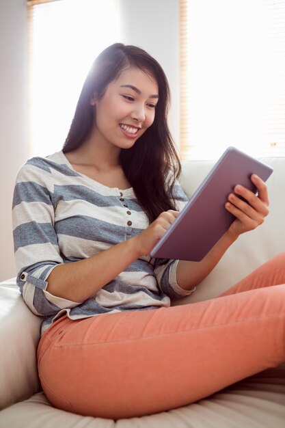 Donna asiatica sorridente che per mezzo della compressa sullo strato