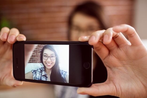 Donna asiatica sul divano prendendo selfie