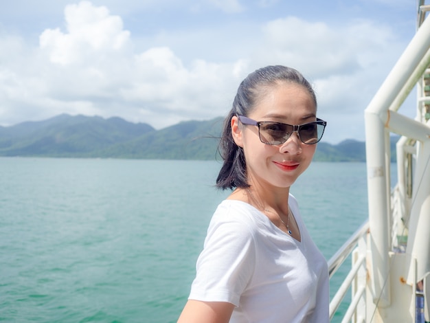 Donna asiatica sul traghetto guardando la vista sul mare.