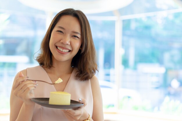 donna asiatica tenta di mangiare a fette di torta al cioccolato al bar caffetteria in pausa dopo il lavoro sentito