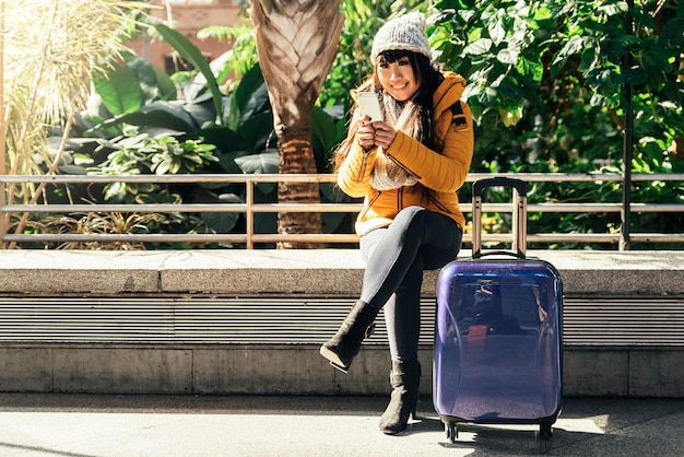 Donna asiatica turistica che utilizza cellulare nella stazione ferroviaria.