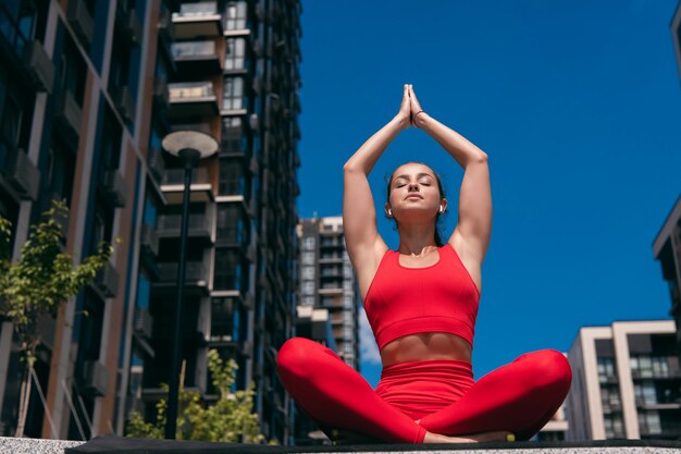 Donna atletica adatta nella posizione di meditazione del loto di yoga con il saluto verso l'alto alle scale