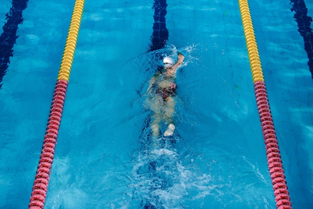 Donna atletica che nuota con cappello e occhiali da nuoto in piscina