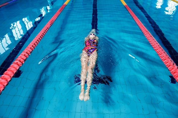 Donna atletica che nuota sulla schiena con in piscina