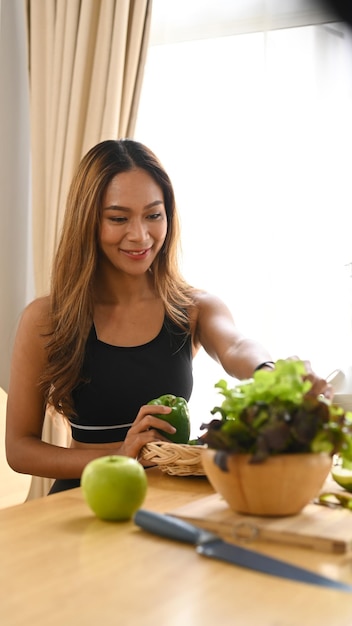 Donna atletica che prepara la preparazione di cibo vegano sano in cucina