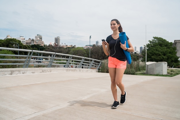 Donna atletica che tiene una stuoia di addestramento.