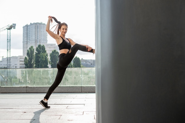 Donna atletica impegnata in atletica leggera, si allena al mattino per strada, una donna fa stretching e trucchi di ginnastica