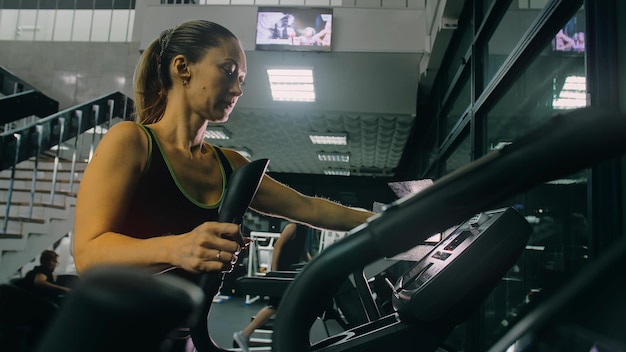 Donna atletica in forma che si esercita su una macchina ellittica Allenamento di attività per donne muscolari nella moderna palestra Allenamento in un trainer ellittico