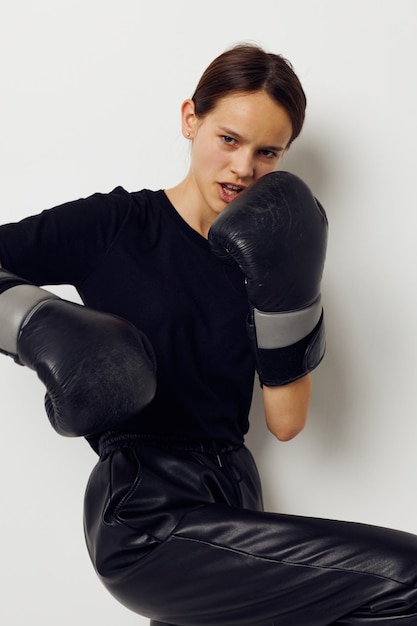 Donna atletica in guanti da boxe in pantaloni neri e una maglietta isolata sullo sfondo