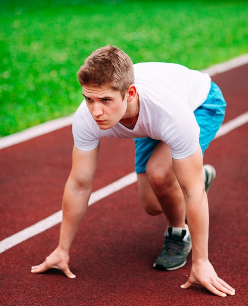 Donna atletica in pista iniziando a correre. Concetto di fitness sano con stile di vita attivo.