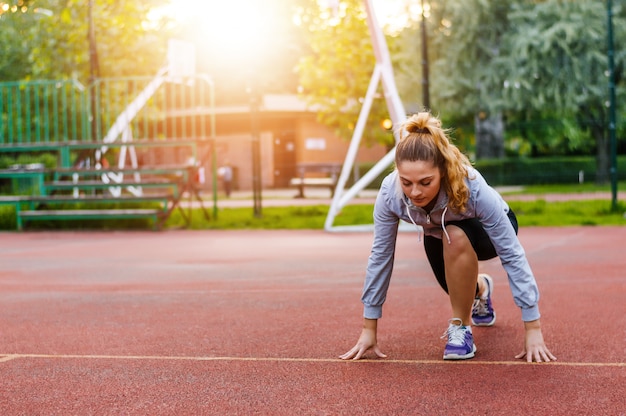 Donna atletica sulla pista di atletica che si prepara per iniziare a correre.