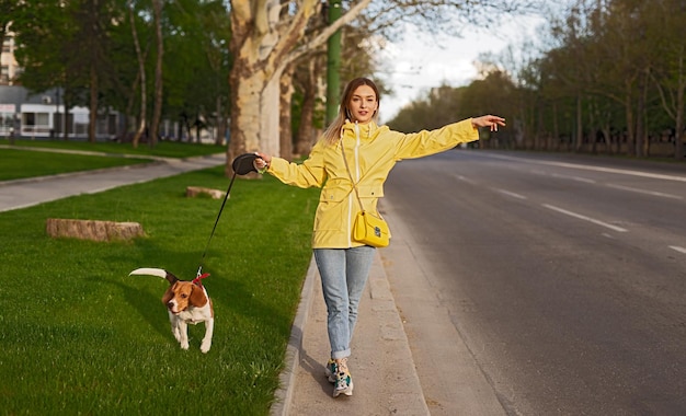 Donna attiva che ottiene auto su strada con il cane al guinzaglio sull'erba