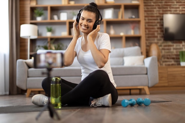 Donna attiva che registra video di allenamento per vlog sportivi tramite telefono