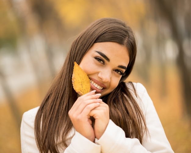 Donna attraente caucasica che sorride e tiene una foglia caduta in autunno