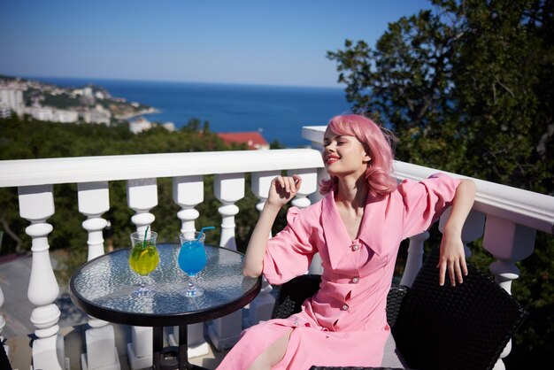 Donna attraente che beve un cocktail sulla terrazza giornata di sole