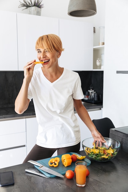 Donna attraente che cucina il pranzo stando in cucina a casa