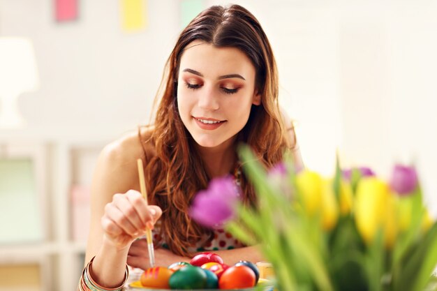 donna attraente che dipinge le uova di Pasqua a casa