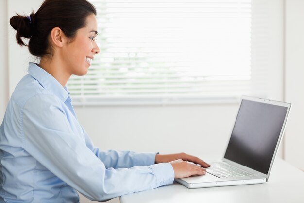 Donna attraente che lavora con il suo computer portatile e che scrive mentre si siedono