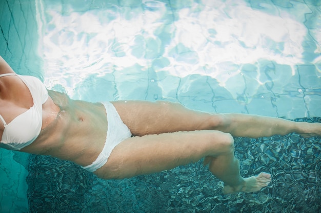 Donna attraente che riposa sul bordo della piscina