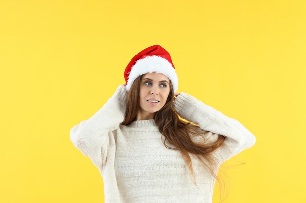 Donna attraente con cappello da Babbo Natale su sfondo giallo