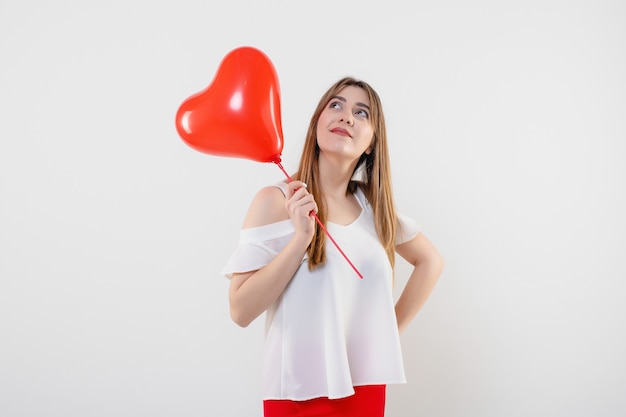 Donna attraente con l'aerostato a forma di cuore rosso isolato