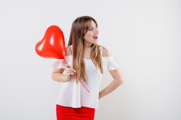Donna attraente con l'aerostato a forma di cuore rosso isolato
