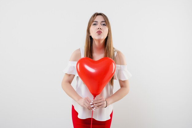 Donna attraente con l'aerostato a forma di cuore rosso isolato