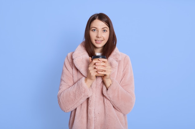 Donna attraente contentissima che sta isolata sopra l'azzurro