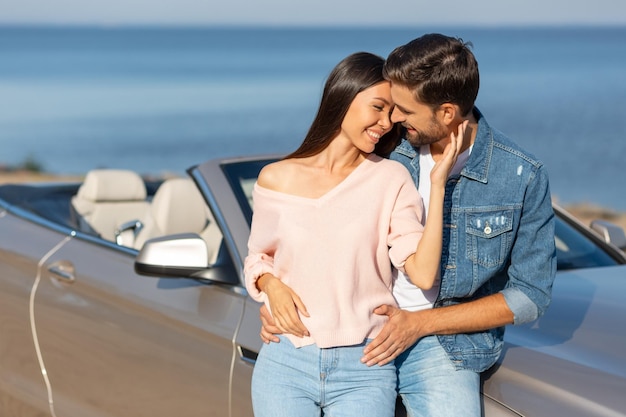 Donna attraente e uomo bello che si abbracciano insieme in piedi all'auto