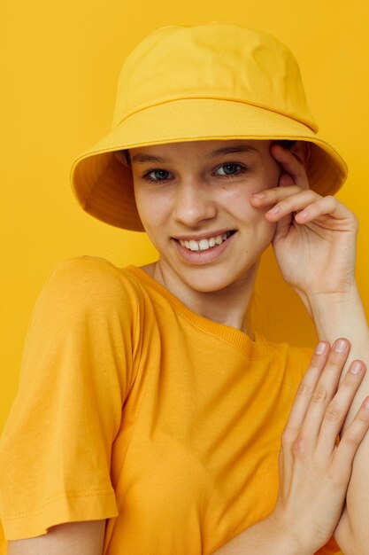 Donna attraente in un cappello giallo stile giovanile abbigliamento casual sfondo giallo