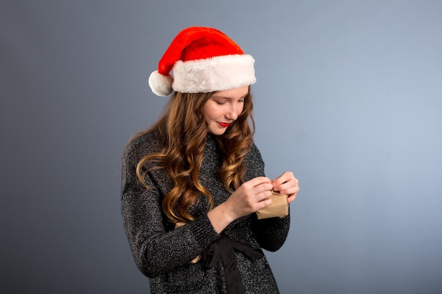 Donna attraente signora indossa il cappello di Babbo Natale Ragazza tiene la scatola che apre il regalo di Natale Ragazza festeggia il Natale Ragazza indossa il cappello di Babbo Natale Ha un regalo per te Regalo da Babbo Natale Sorpresa sexy