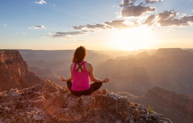 Donna avventurosa del viaggiatore che fa meditazione sul paesaggio americano della montagna rocciosa del deserto