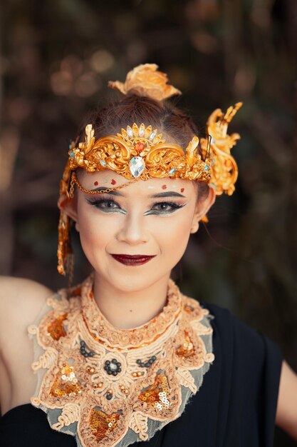 Donna balinese che indossa una corona d'oro e una collana d'oro nel suo trucco con un bel viso