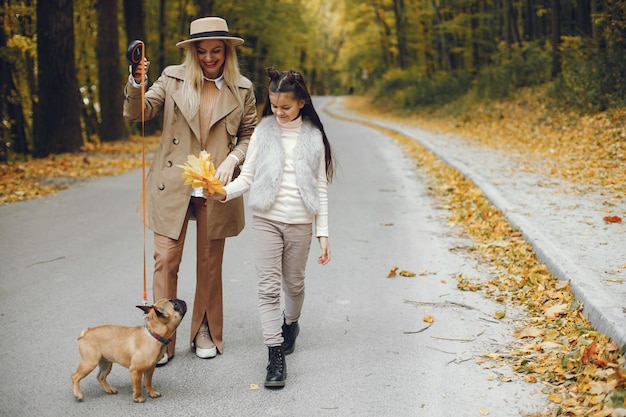 Donna, bambina e cane che camminano nel parco autunnale