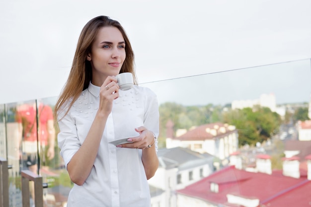 Donna bianca rossa in camicia bianca, bere il caffè