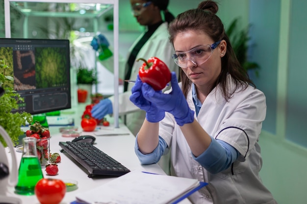 Donna biologa che esamina pepe che scrive competenze mediche di microbiologia sul blocco note per analizzare l'agricoltura