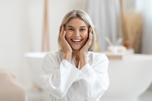 Donna bionda attraente che tocca il suo viso e sorridente